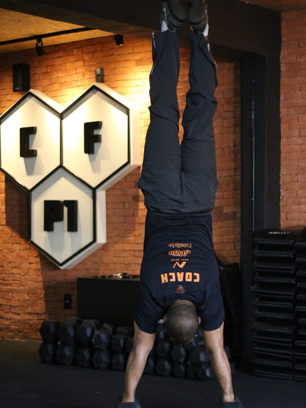 Vandeyr em handstand push-up apoiado em halteres, de ponta-cabeça, no box
